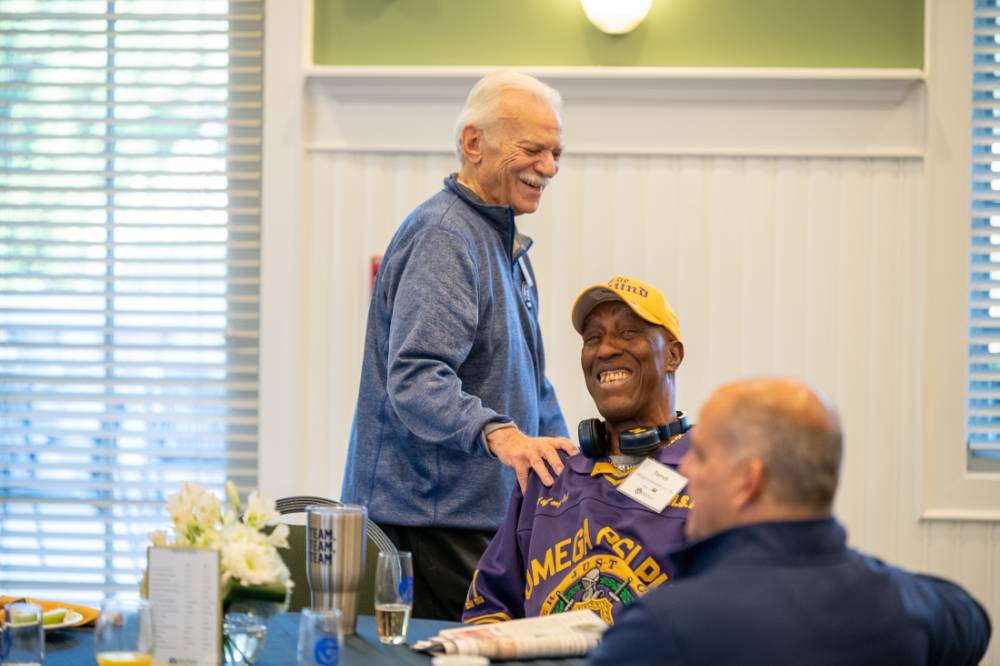An alumni putting his hand on another alumni's shoulder.